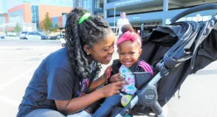 woman leaning over at her daughter in a stroller