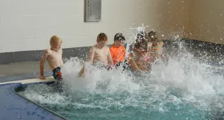 kids in the end of a pool kicking up a bunch of water