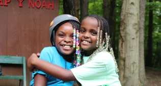 two girls hugging at the alpine tower at camp Y-Noah
