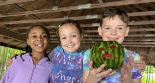 three campers with one on the end holding a watermelon