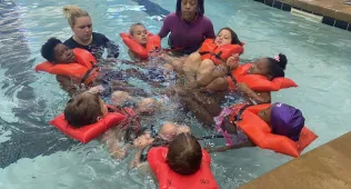 Group of kids in lifejackets learning how to swim
