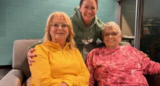 Three women smiling at the camera on a couch
