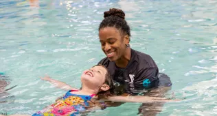 Swim instructor helping a student float