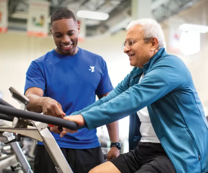 Fitness instructor helping member on a bike