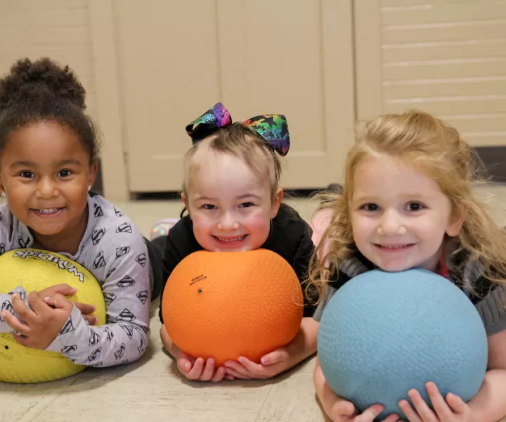 three girls holding balls