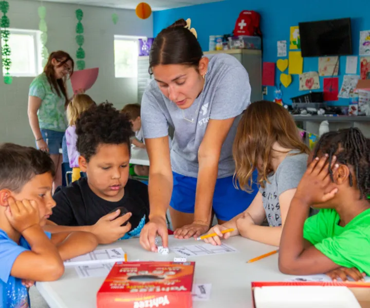Camp counselor teaching campers how to play a game