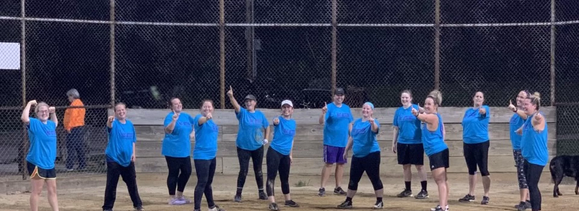 Group of women playing softball pointing at the camera