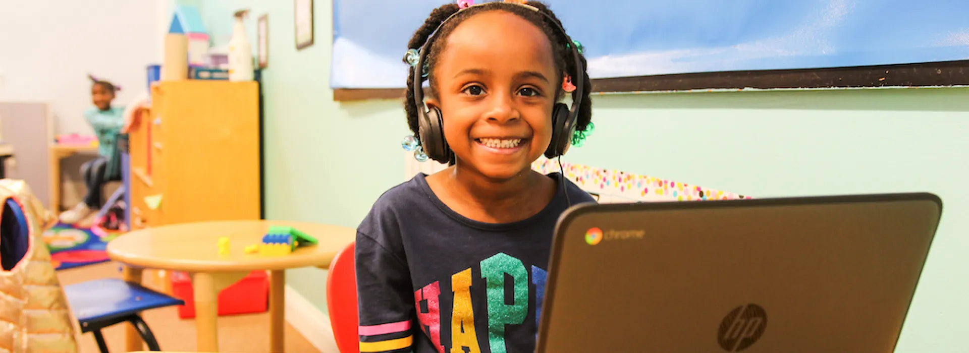 Little girl with headphones at computer