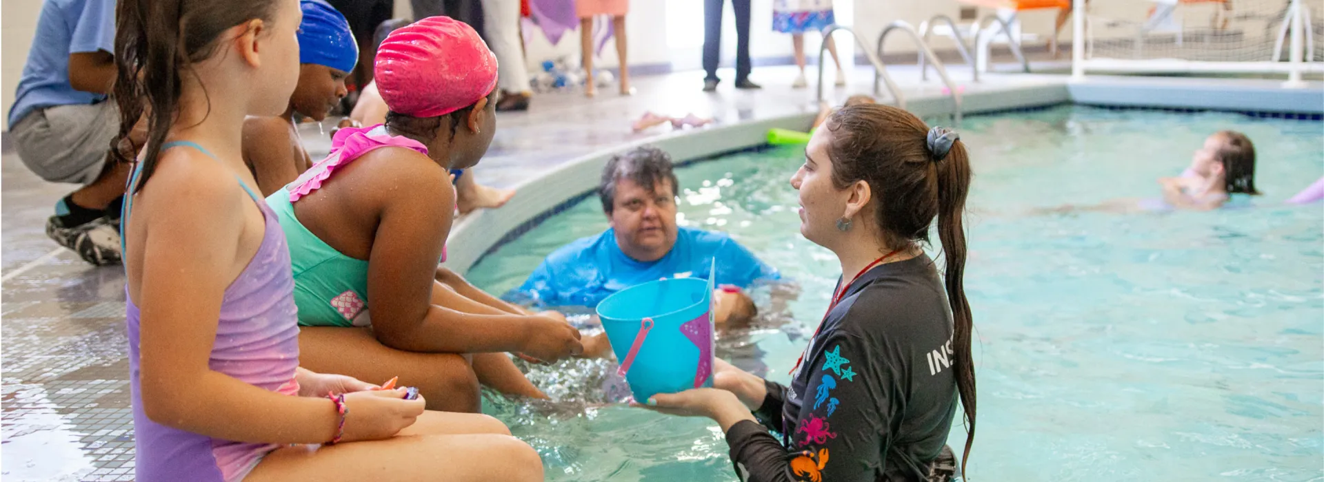 Children sitting on the edge of a pool during a lesson